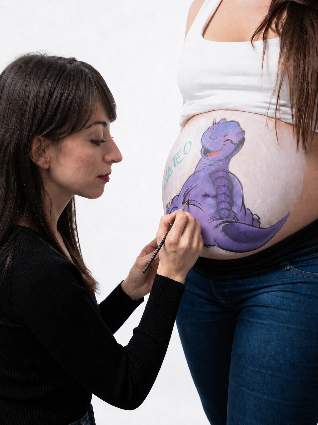 Ángela realizando bellypainting a una embarazada con un diseño de dinosaurio